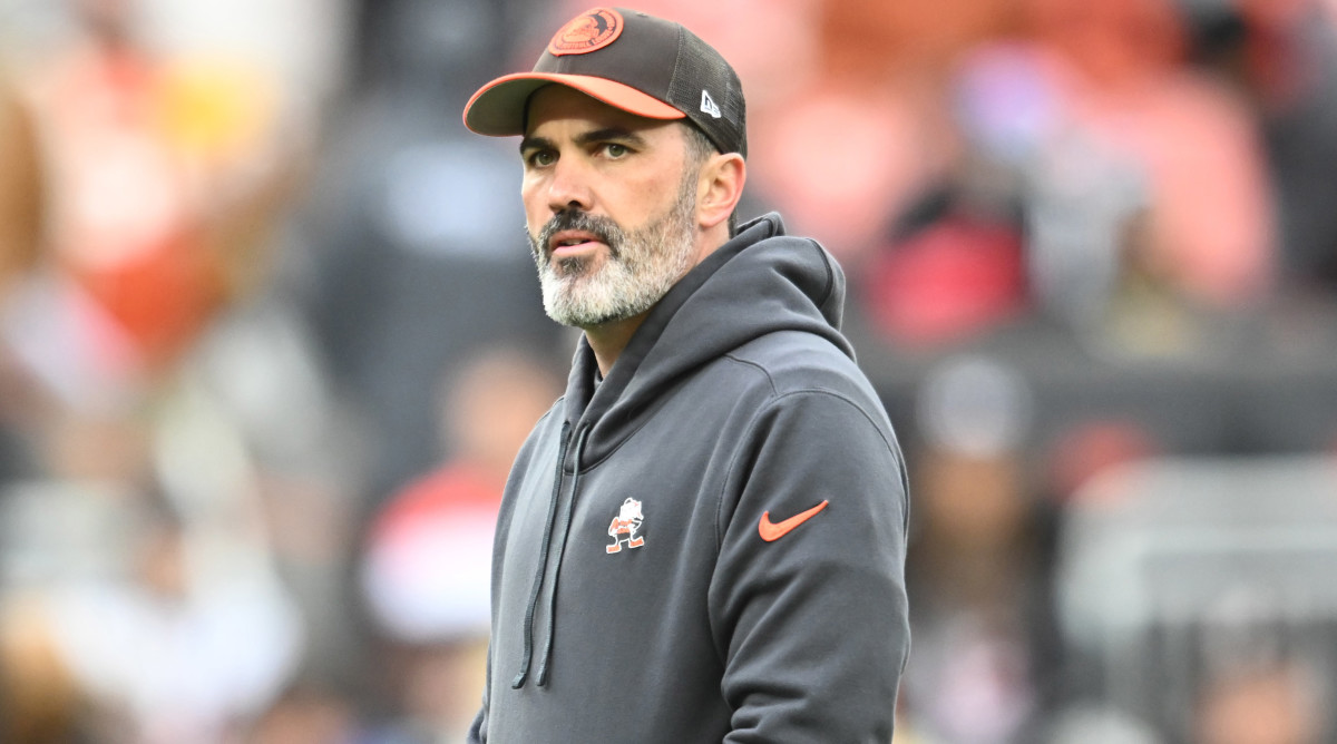 Kevin Stefanski stands looking to the side wearing a Browns hat and sweatshirt